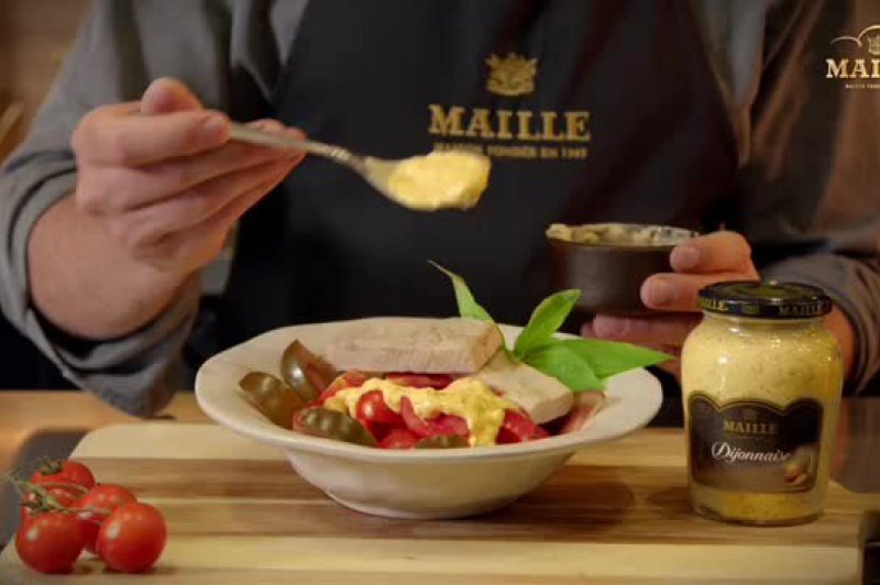 Chef con delantal negro preparando en un bol blanco ensalada de tomate, ventresca de bonito con vinagreta Dijonnaise
